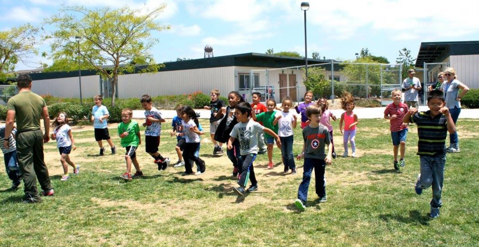 Adult and children running on a grassy field