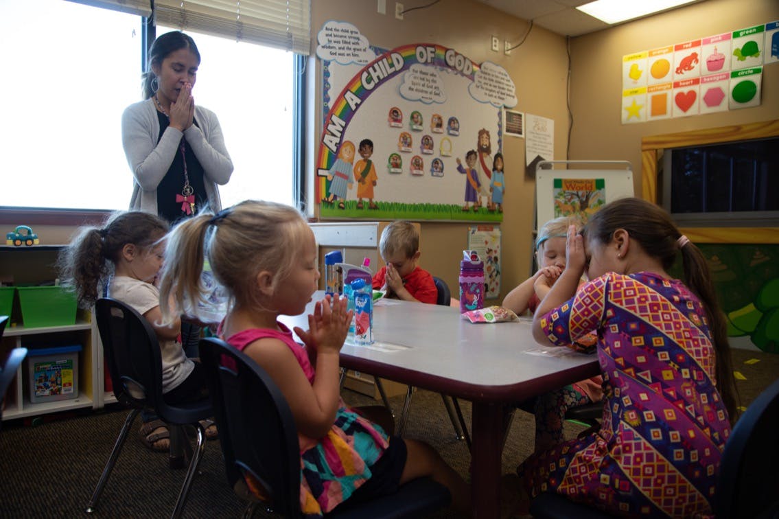 Adult and children with hands together in a classroom