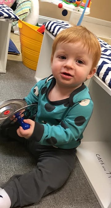 Child sitting on floor holding a toy