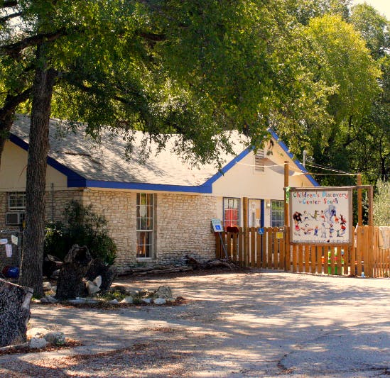 Building with a blue roof and a wooden fence with a sign