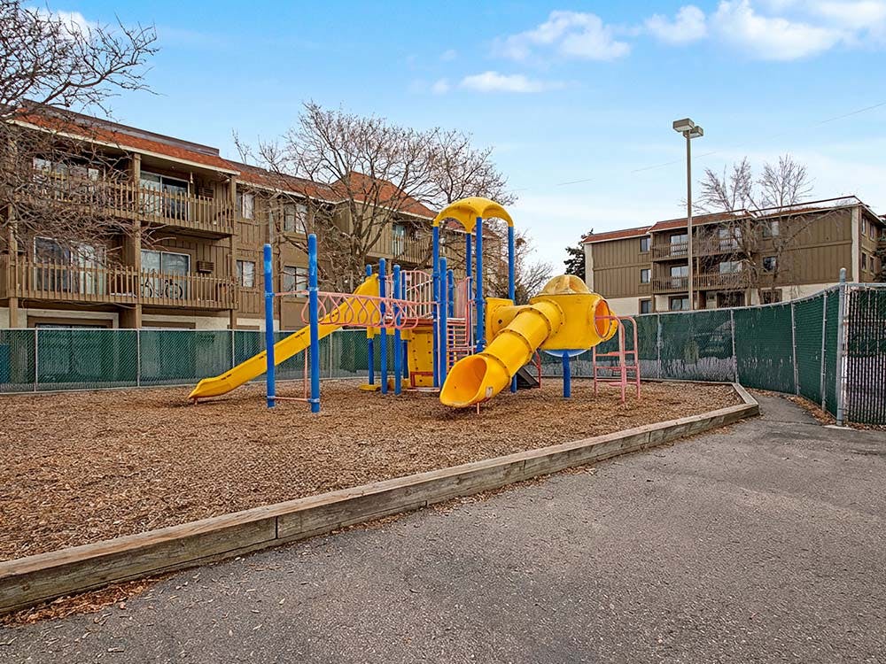 A colorful playground with yellow slides and blue poles on a wood chip surface