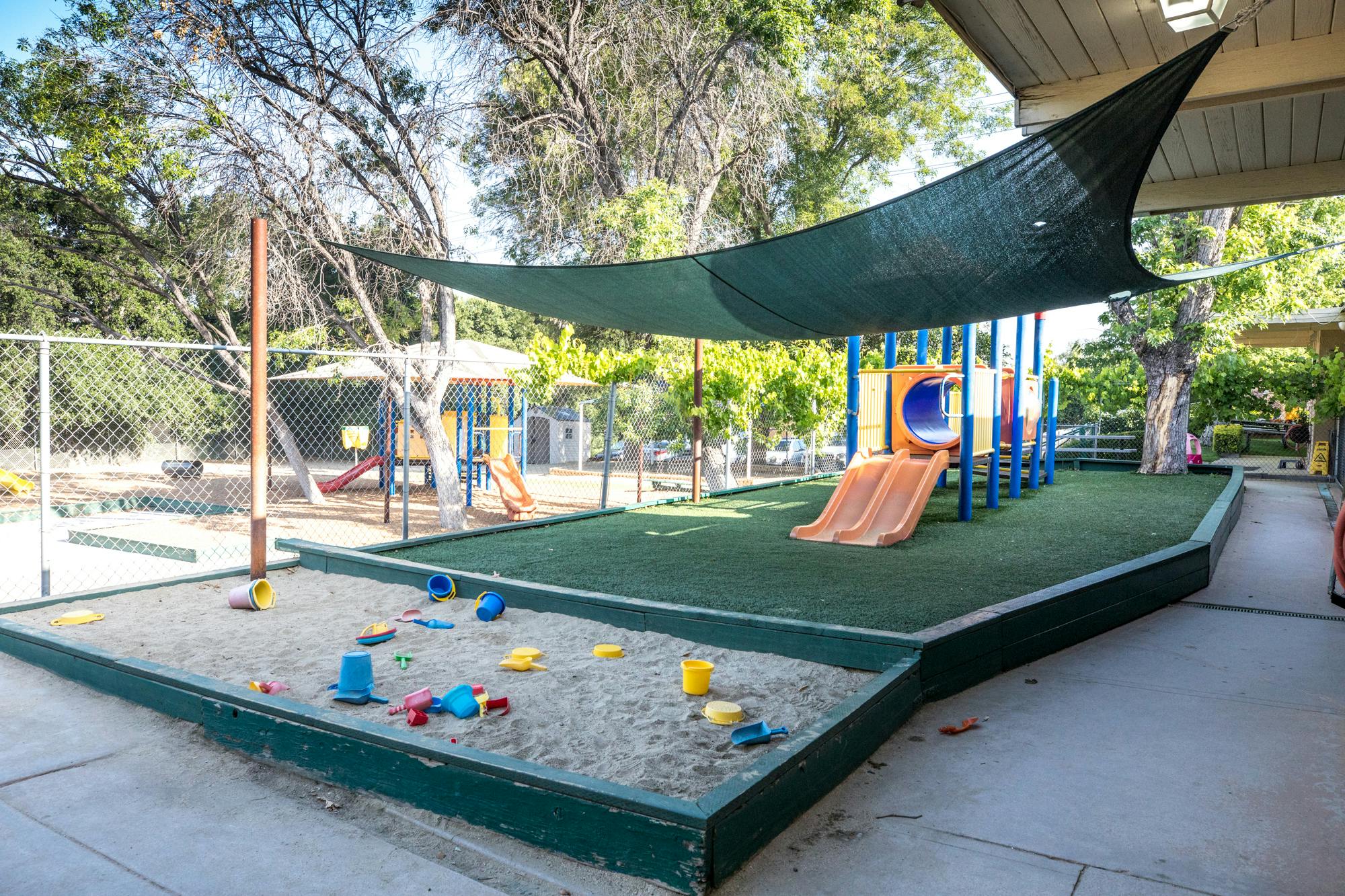 Playground with sandbox, slide, and shade canopy