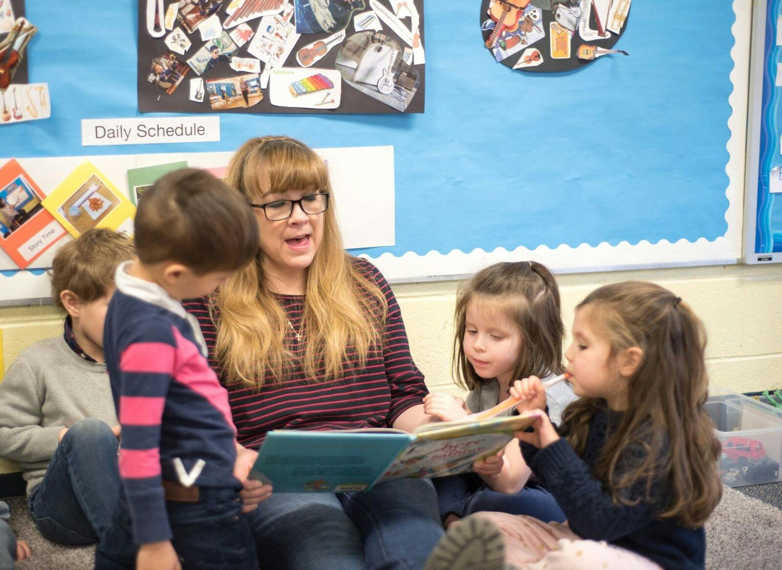 Adult reading a book to children in a classroom