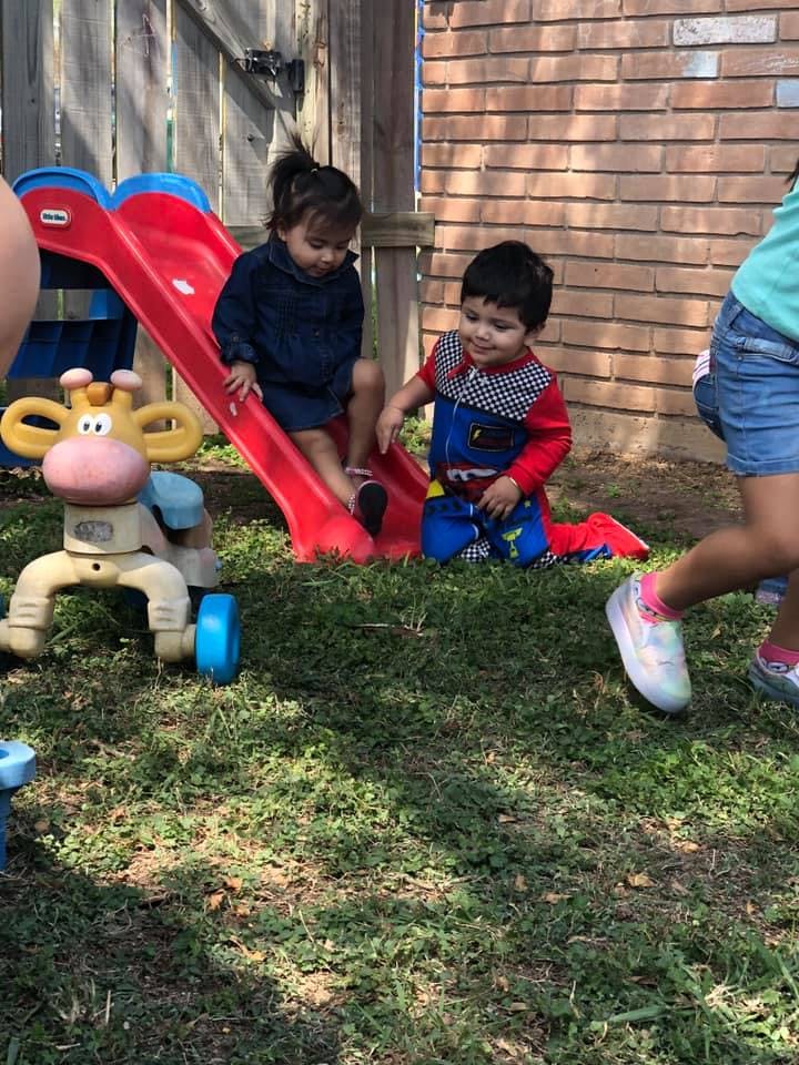 Two children playing on a red slide outdoors