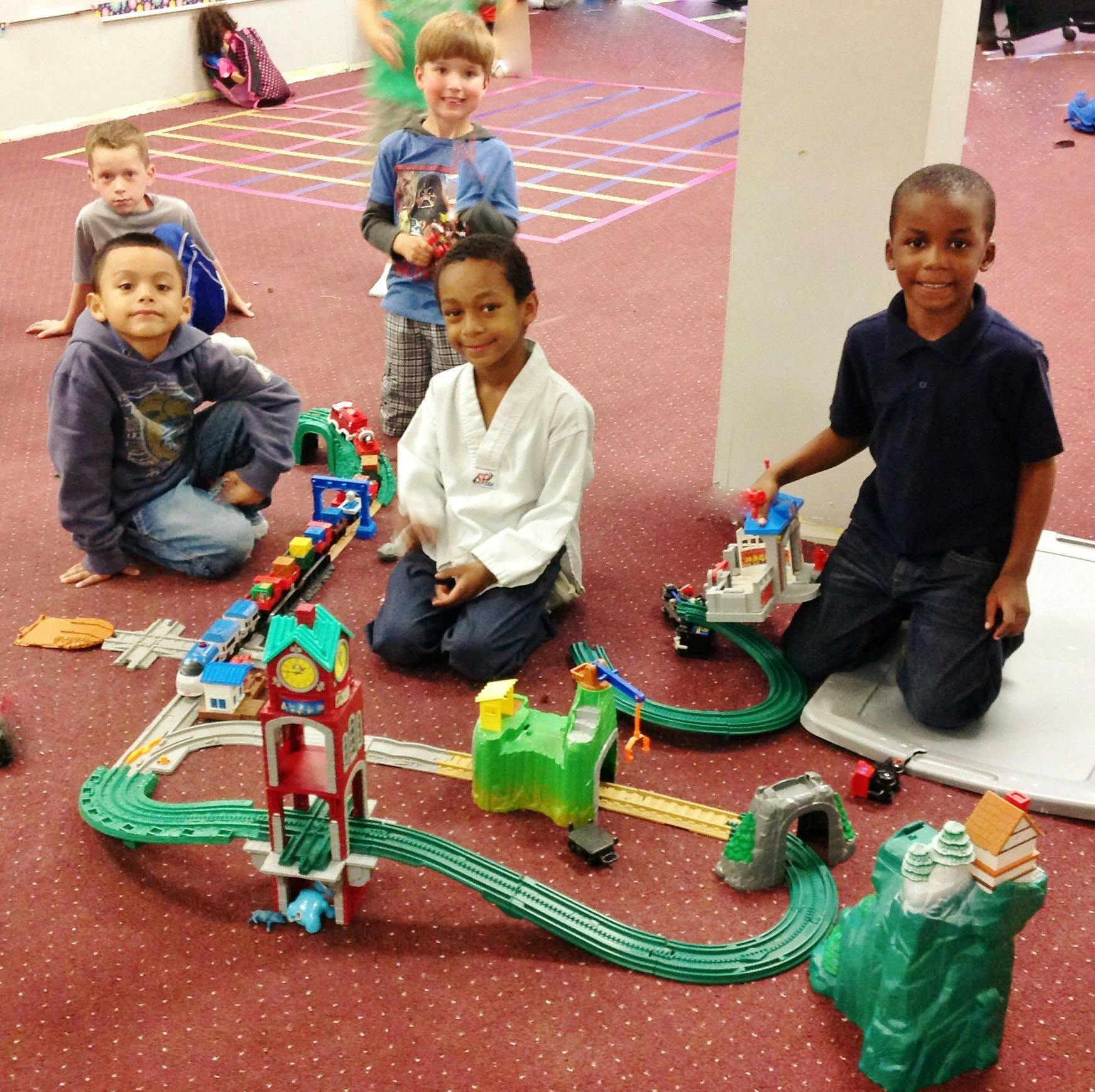 Children playing with a toy train set on the floor