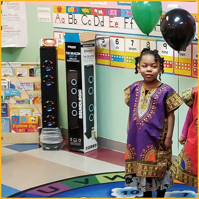 Child in a purple patterned dress standing in a classroom