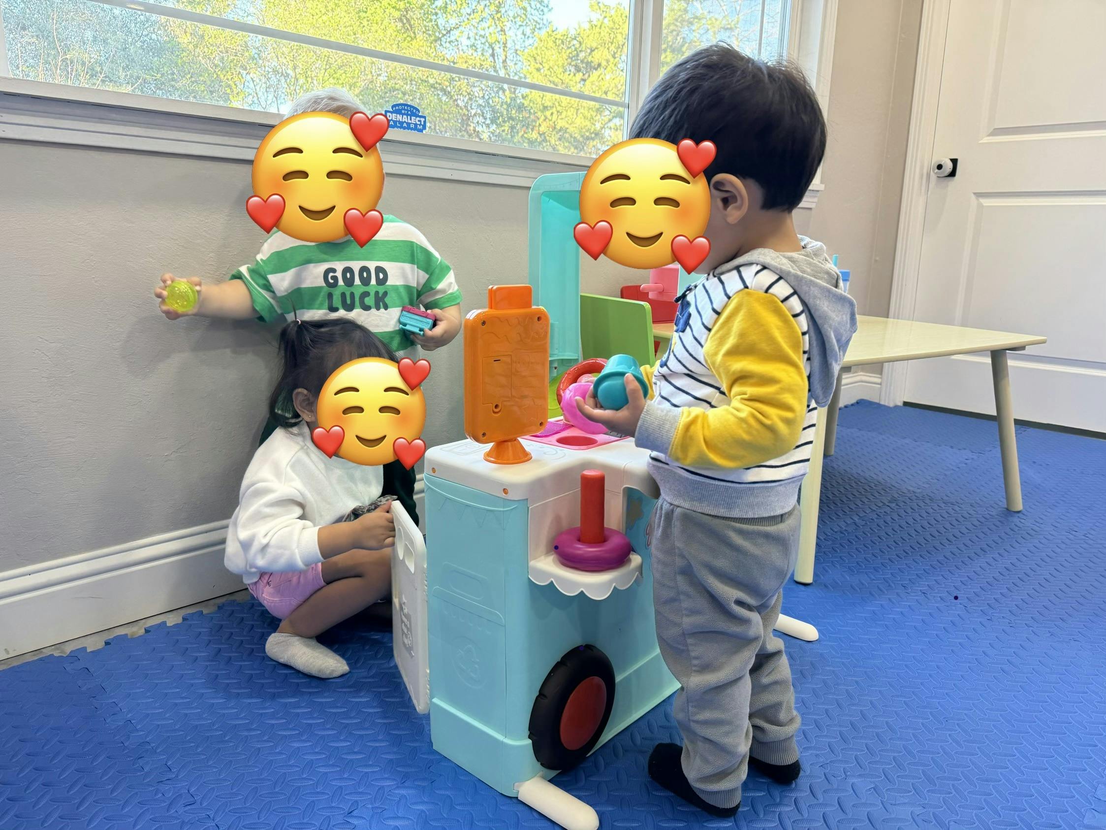 Three children playing with a toy food cart in a room