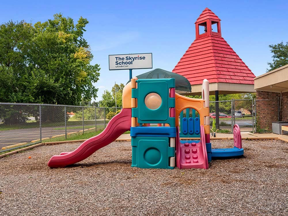 A colorful playground with a slide and climbing structure on wood chips