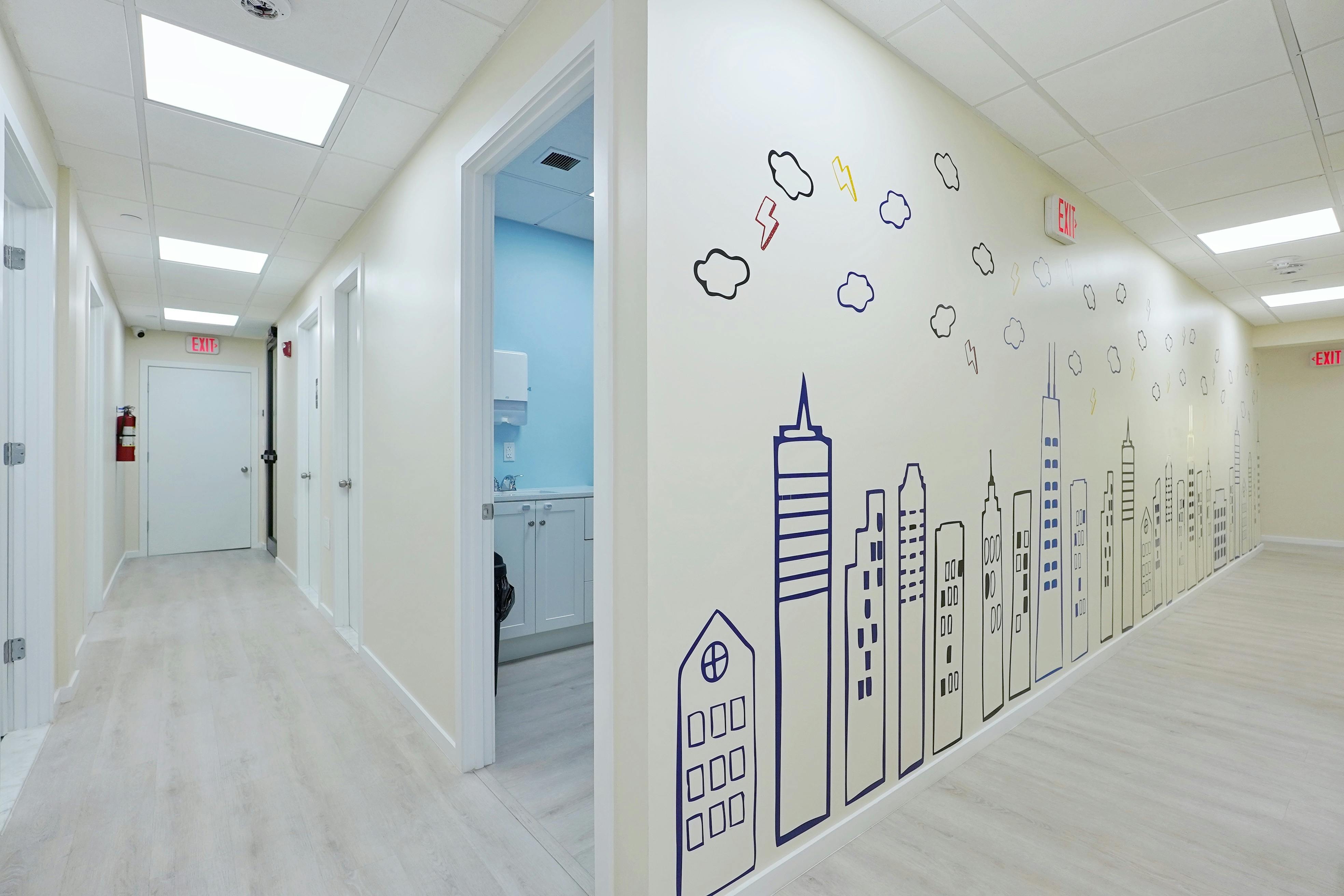 Hallway with doors and a wall mural of a city skyline