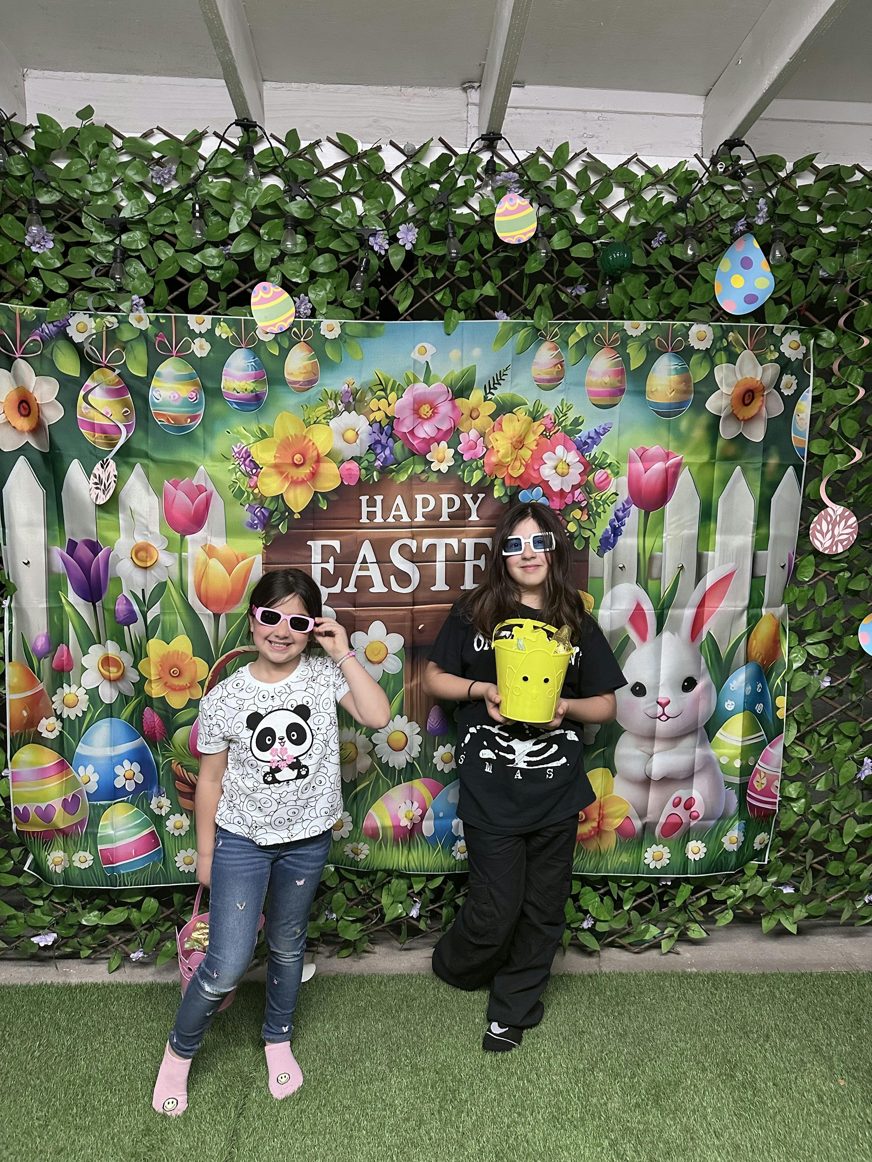 Two children standing in front of an Easter backdrop holding baskets