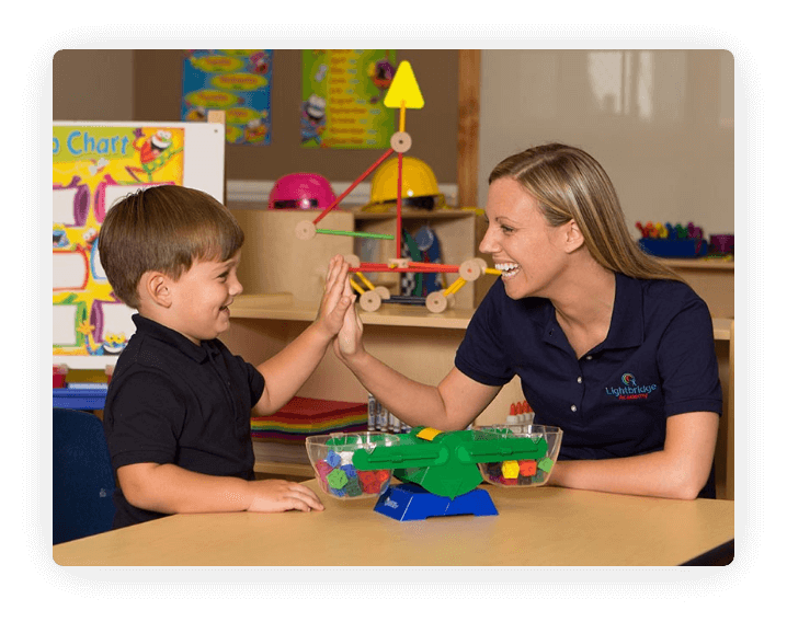 Adult and child high-fiving in a classroom
