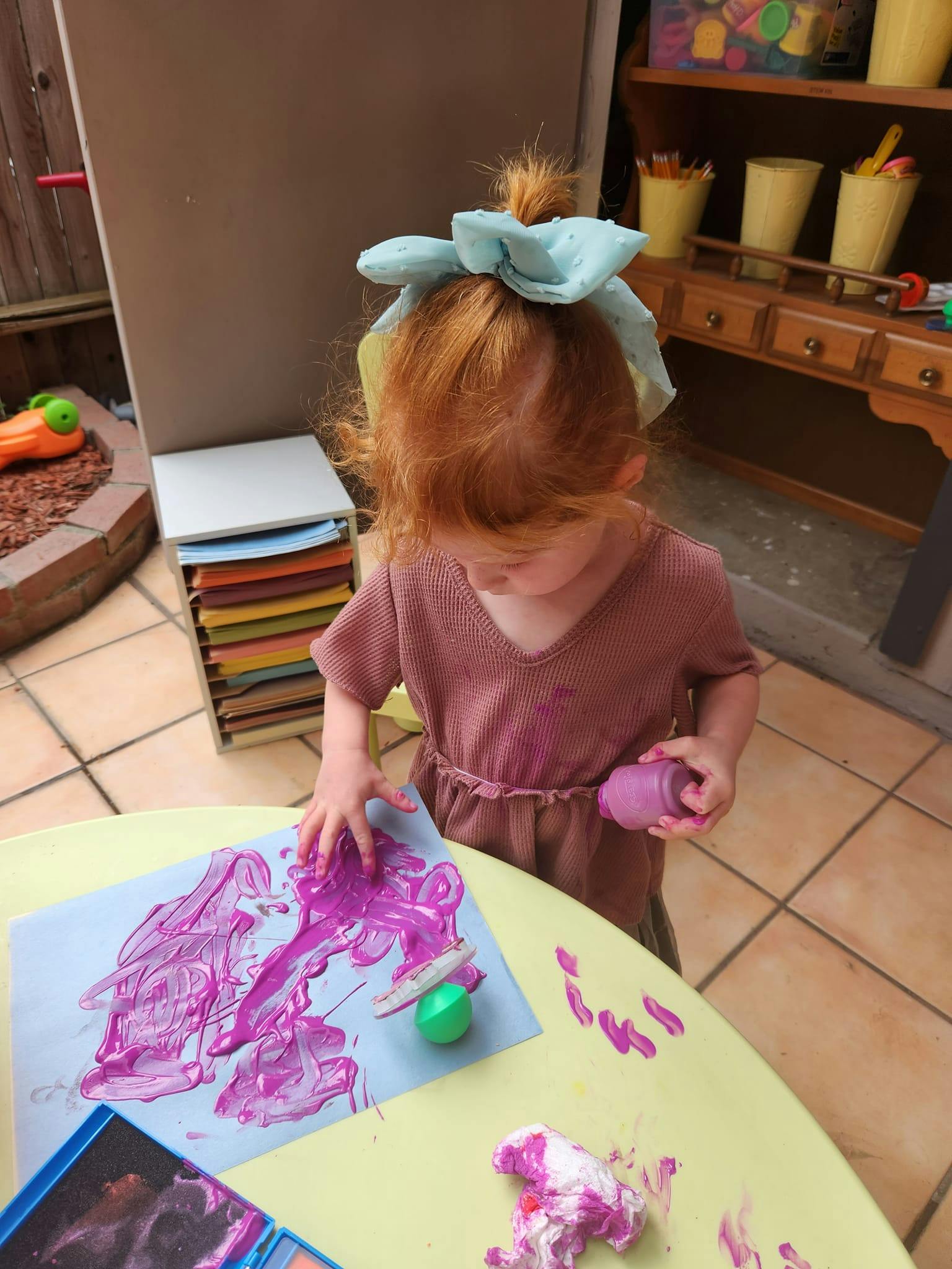Child painting with purple paint on a table