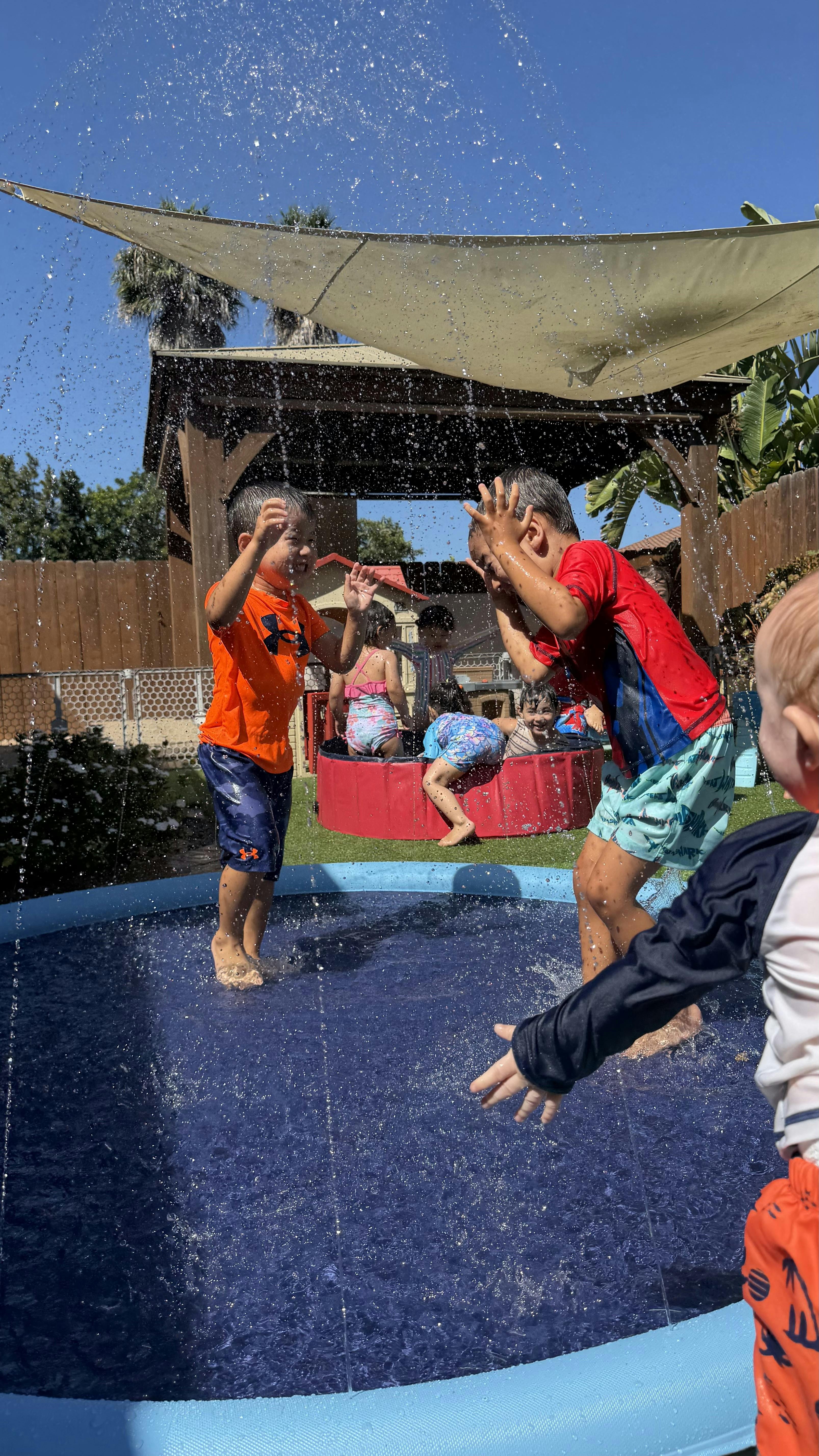 Children playing in a splash pool in a backyard