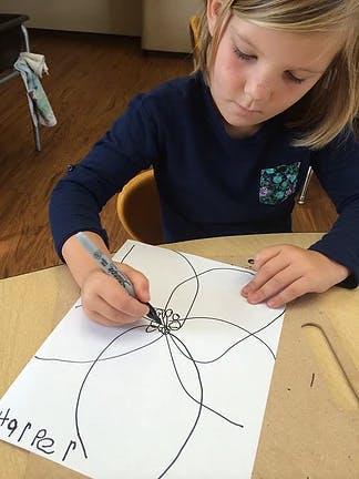 Child drawing on paper with a marker