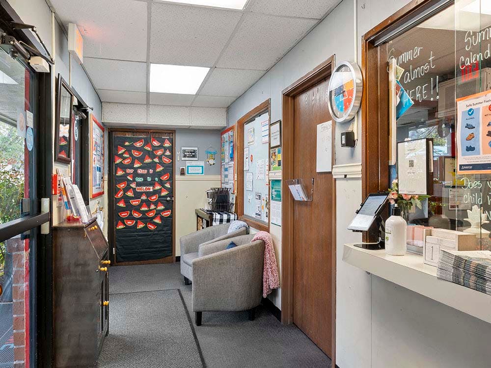Waiting area with two chairs, a reception desk, and a door decorated with watermelons
