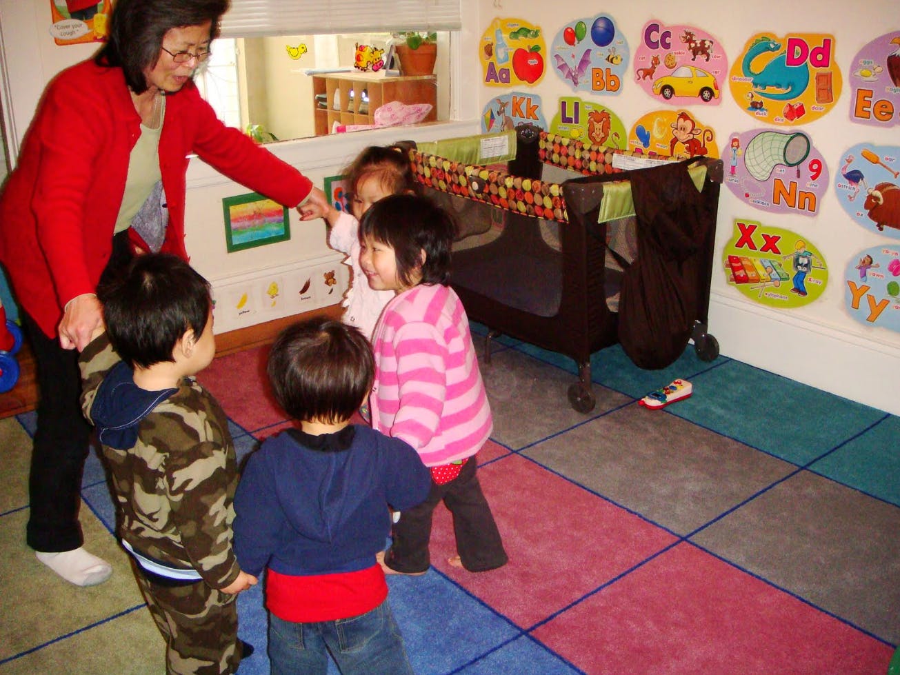 Adult person interacting with three children in a classroom