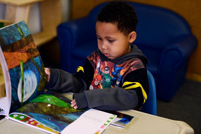 Child looking at an open book with colorful illustrations
