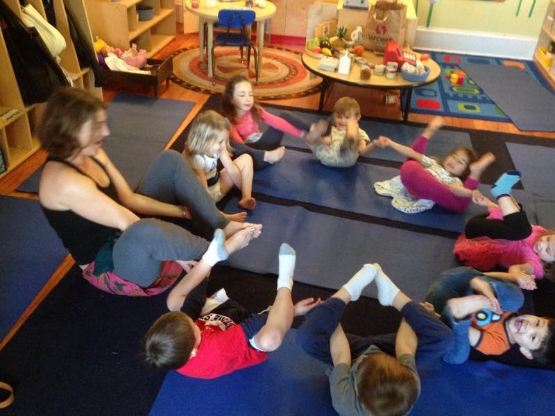 Adult and children sitting in a circle on mats
