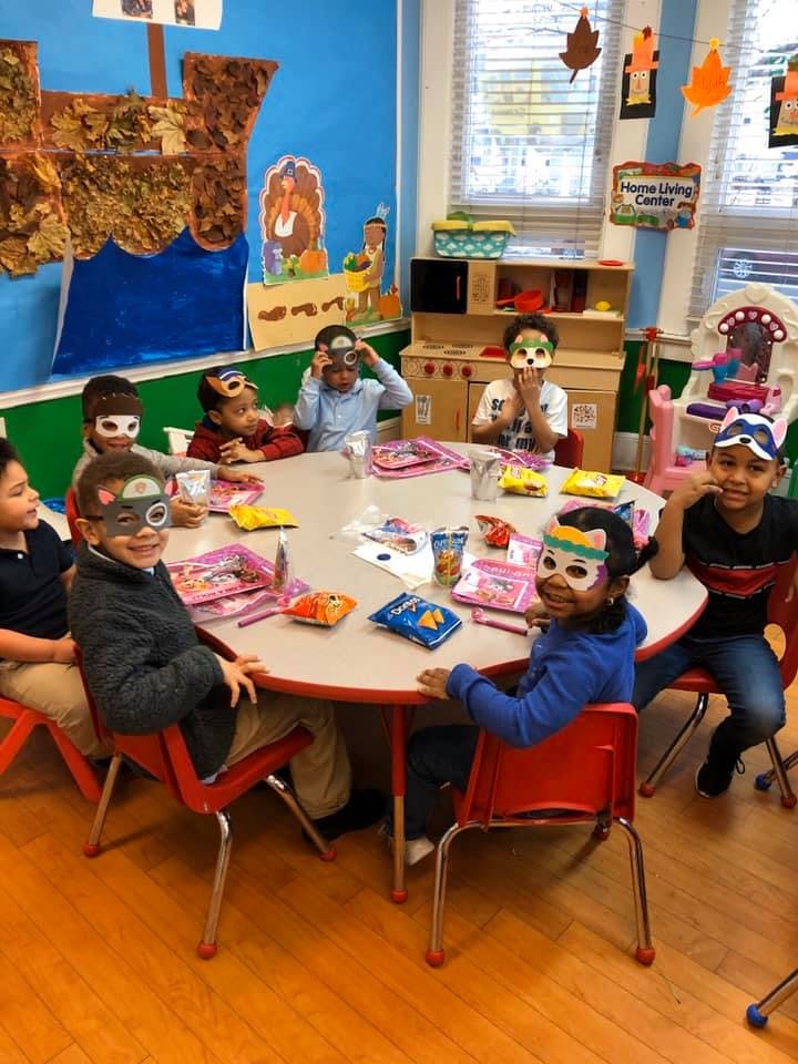 Children wearing masks sitting around a table in a classroom