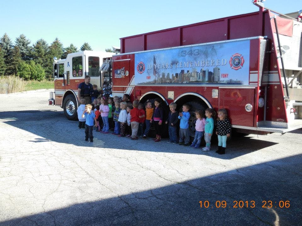 Children standing in a line next to a fire truck