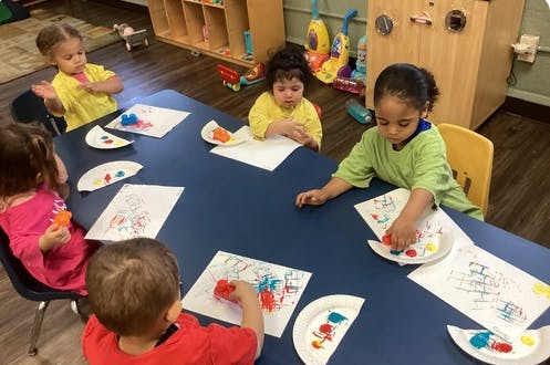Children at a table doing an art activity with paint and paper plates