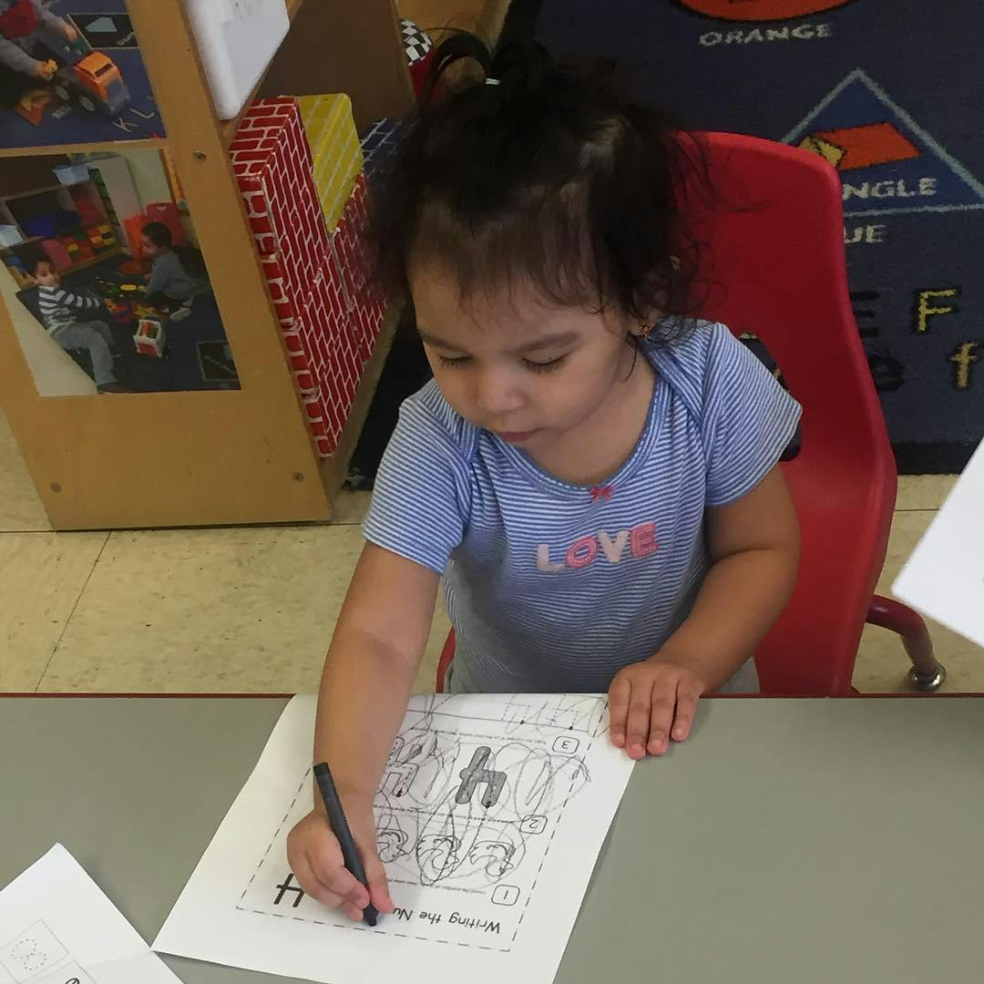 Child writing on a worksheet in a classroom