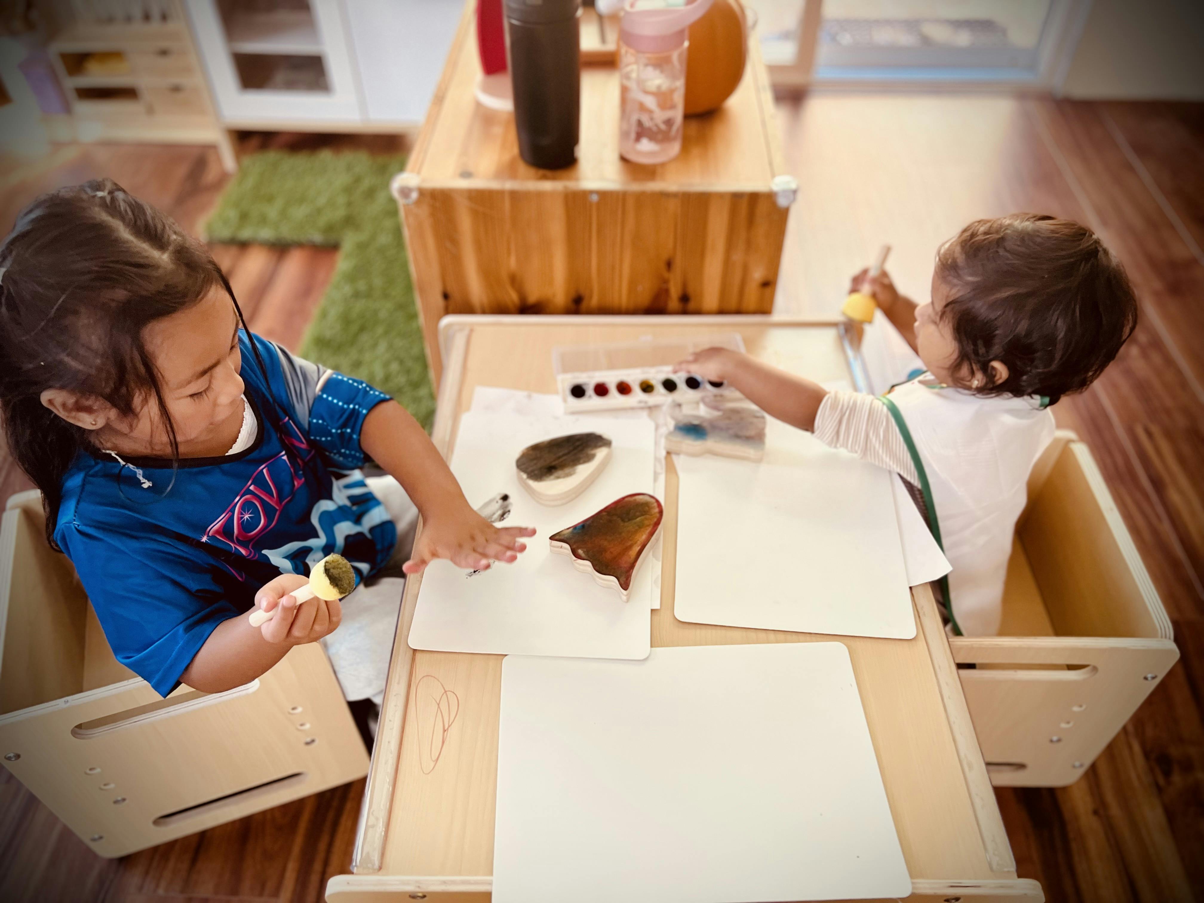 Two children painting at a table