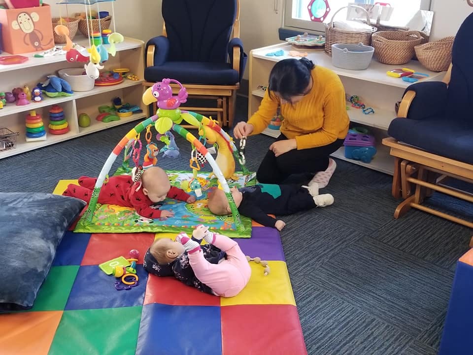 Person interacting with babies on playmats in a room