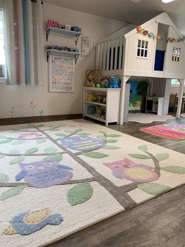 Playroom with an owl-patterned rug and a small playhouse