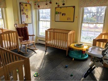 Cribs and baby activity toys in a room with windows