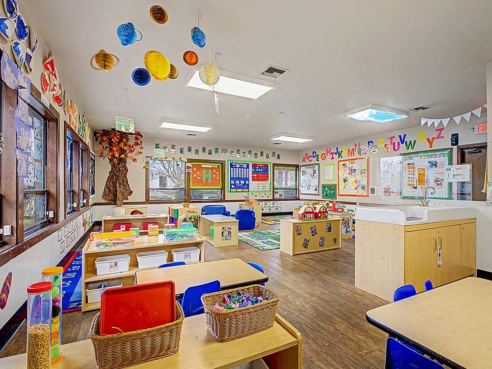 Bright, colorful preschool classroom with small tables and chairs