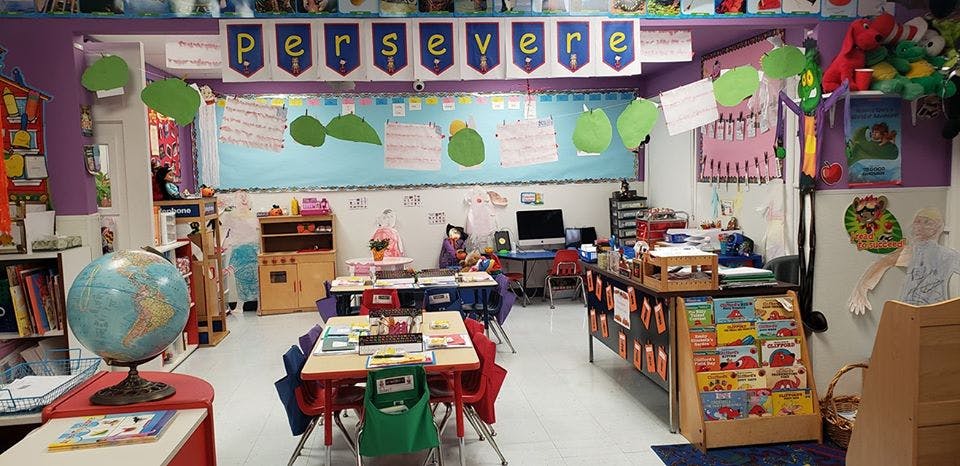 Classroom with small tables and chairs, a globe, and a banner that reads "persevere"