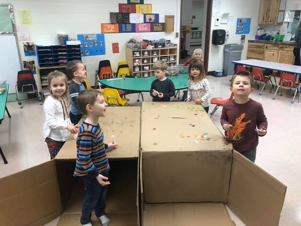 Children playing with cardboard boxes in a classroom