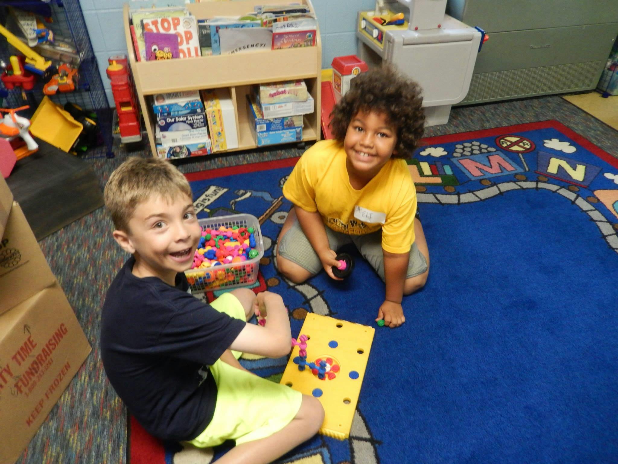 Two children playing with toys on a rug