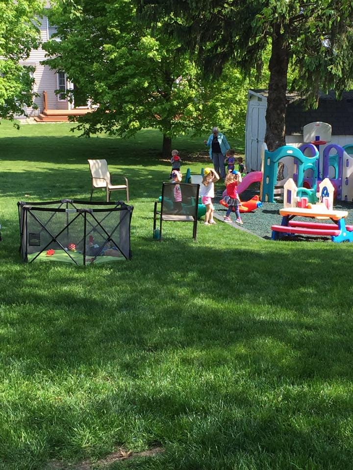 Children playing in a grassy yard with outdoor toys and playground toys
