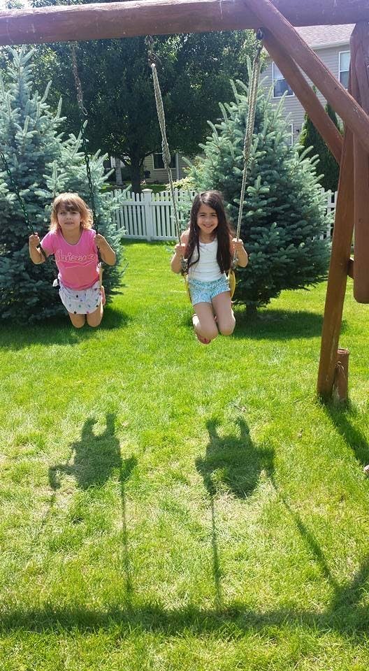 Two children on swings in a grassy yard