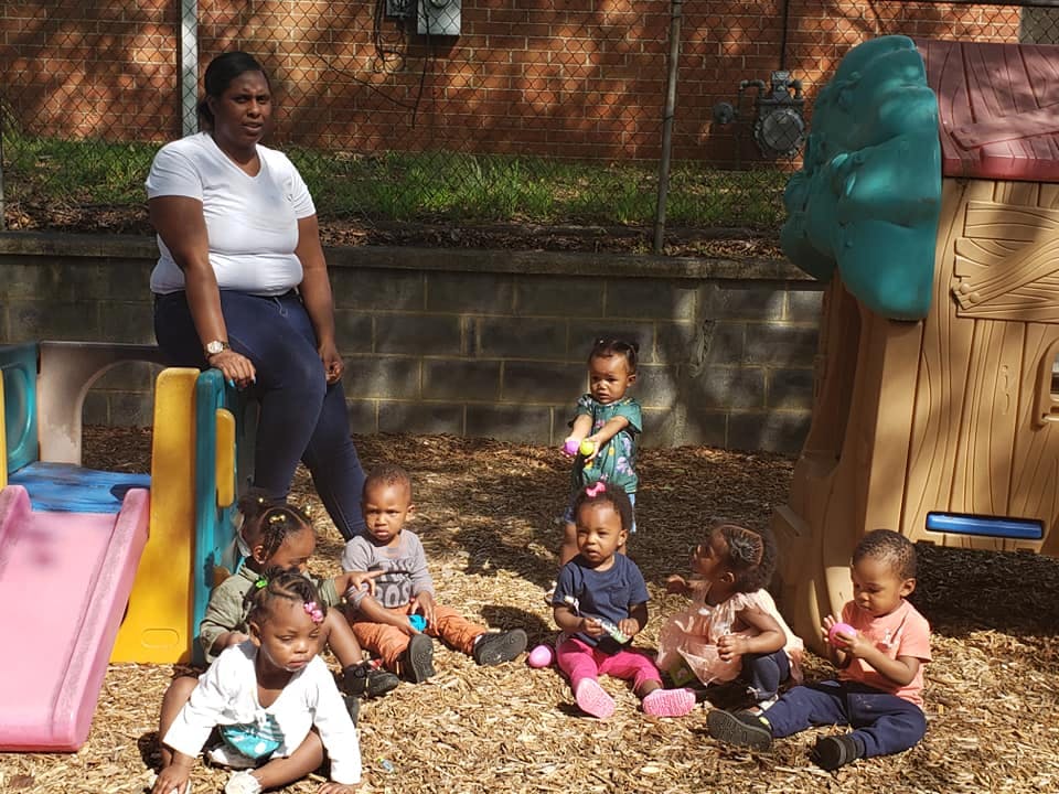 Adult person sitting on a play structure with several children on the ground