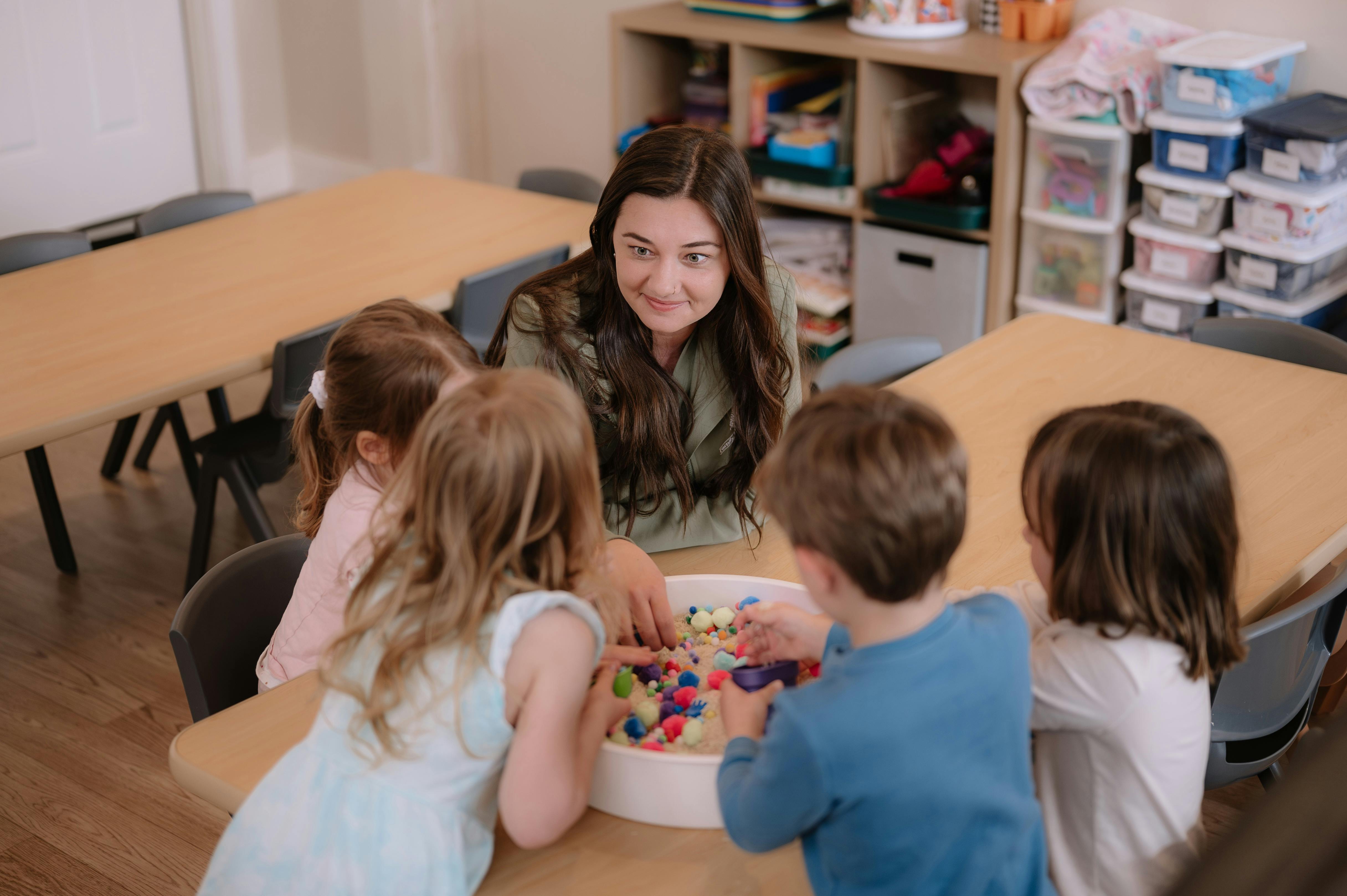 Person and children playing with colorful objects in a classroom