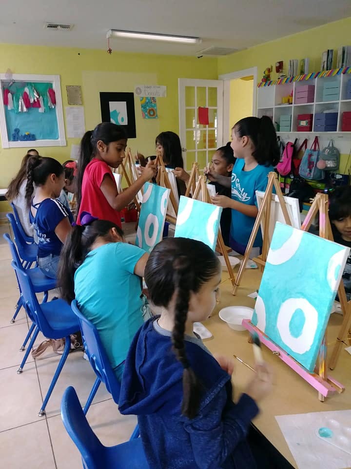 Children painting on canvases in a classroom