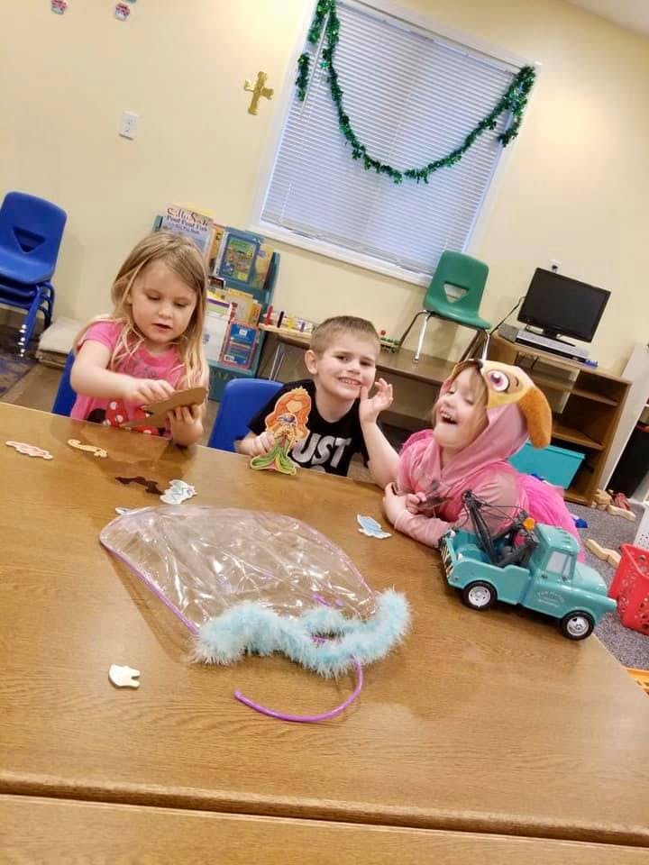 Three children playing at a table with toys