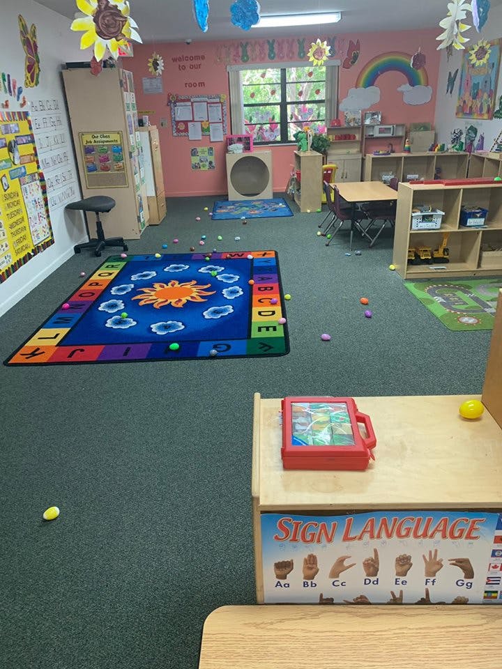 Classroom with a colorful rug, tables, and shelves