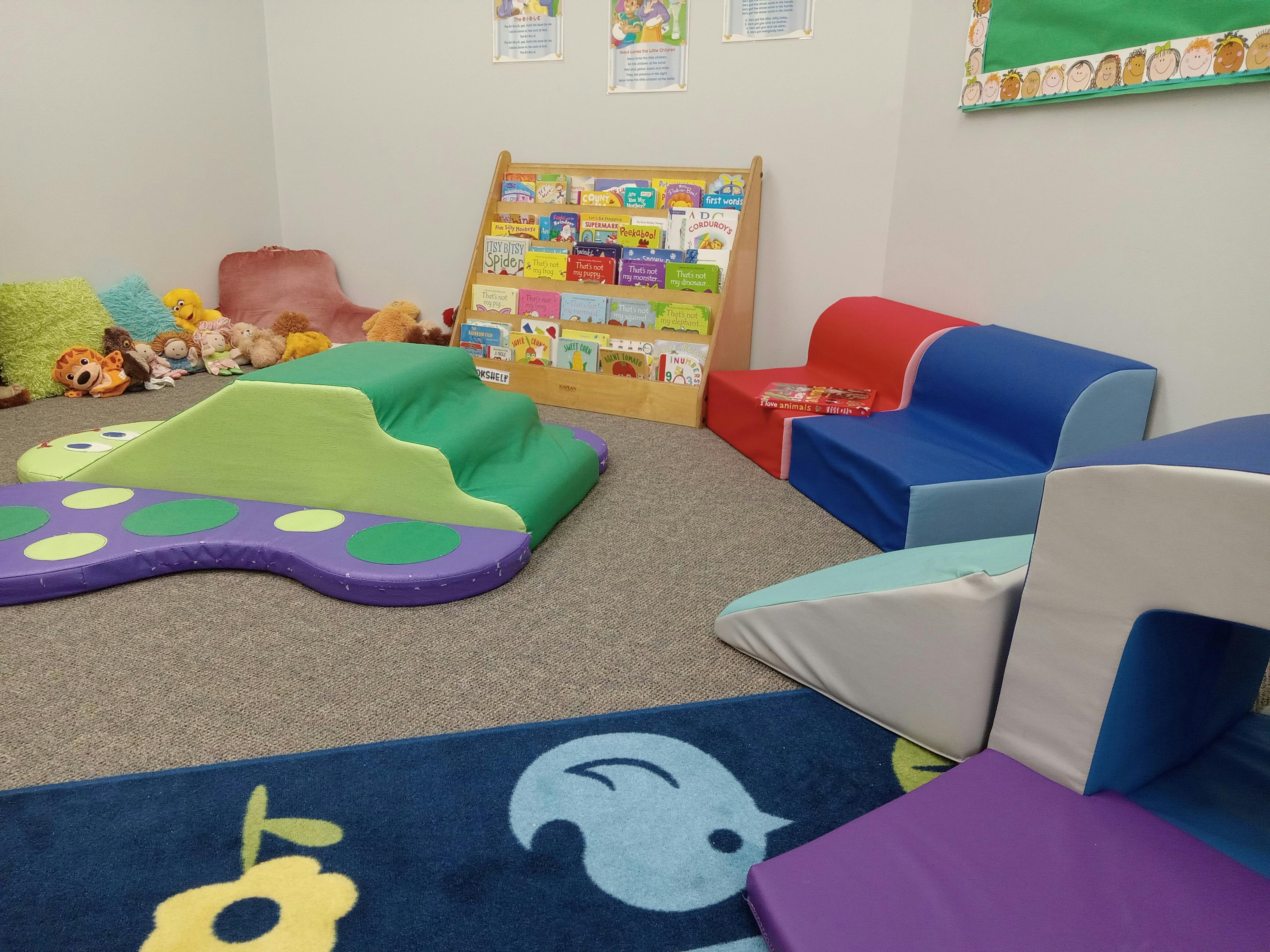Children's play area with soft play equipment and a book display