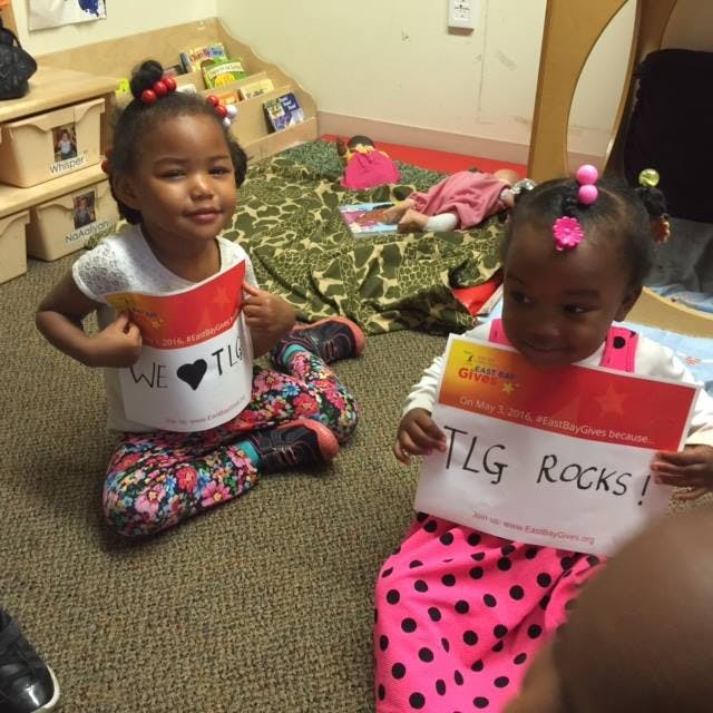 Two children sitting on the floor holding signs