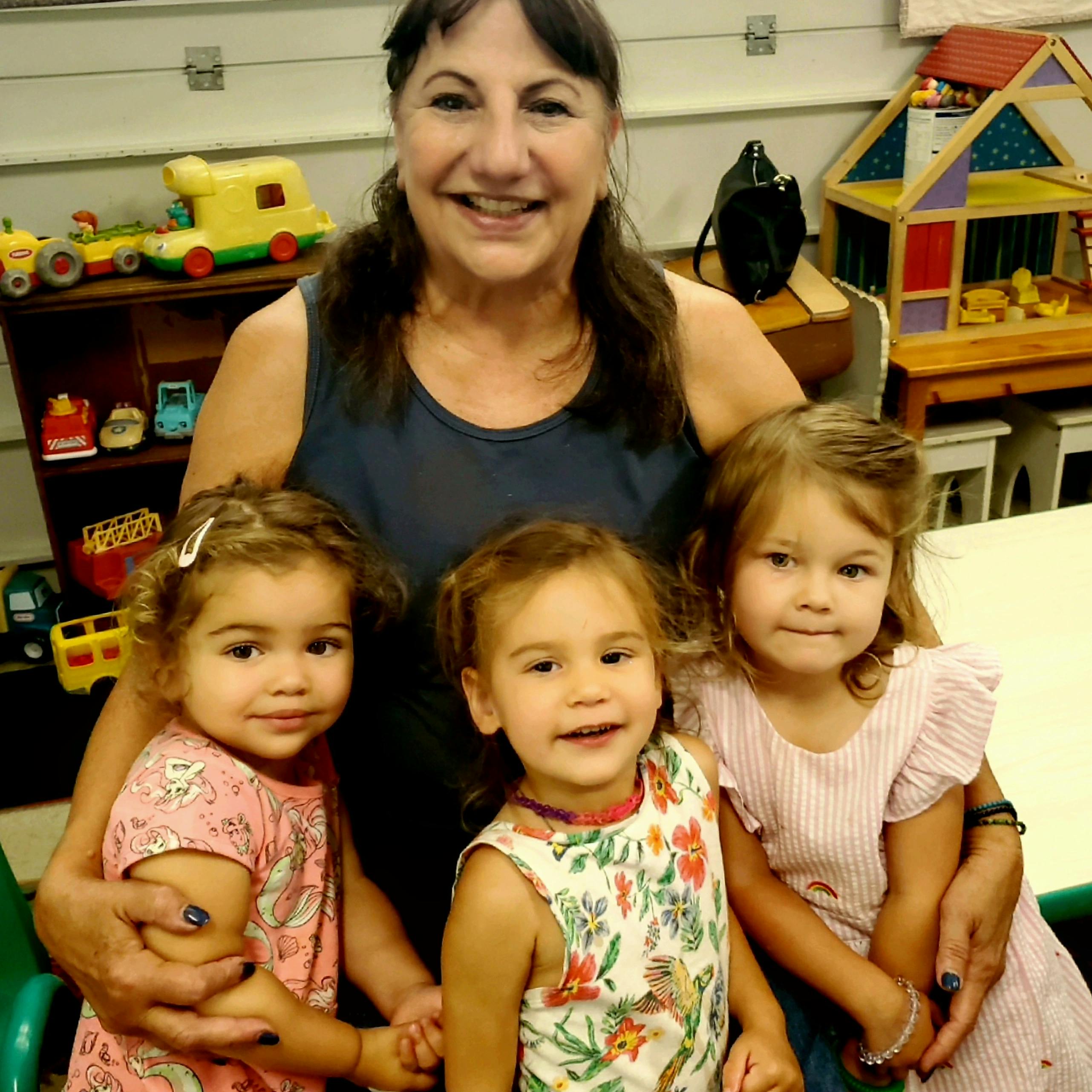Person with three children in a classroom