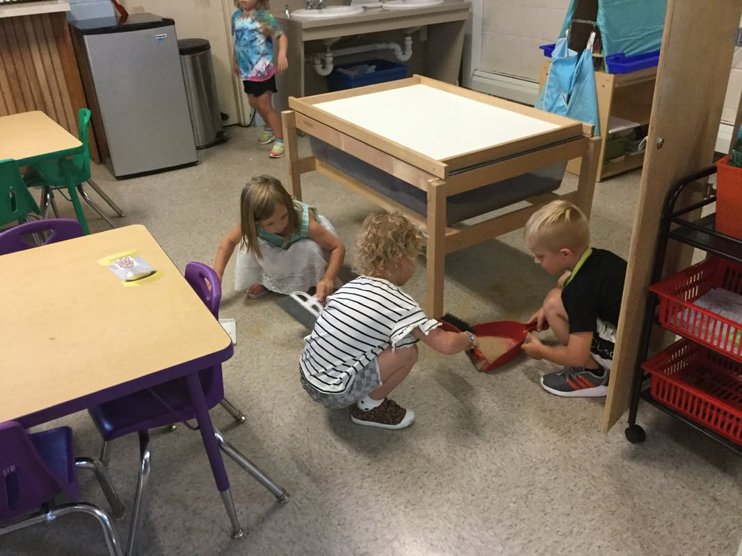 Three children playing on the floor in a classroom