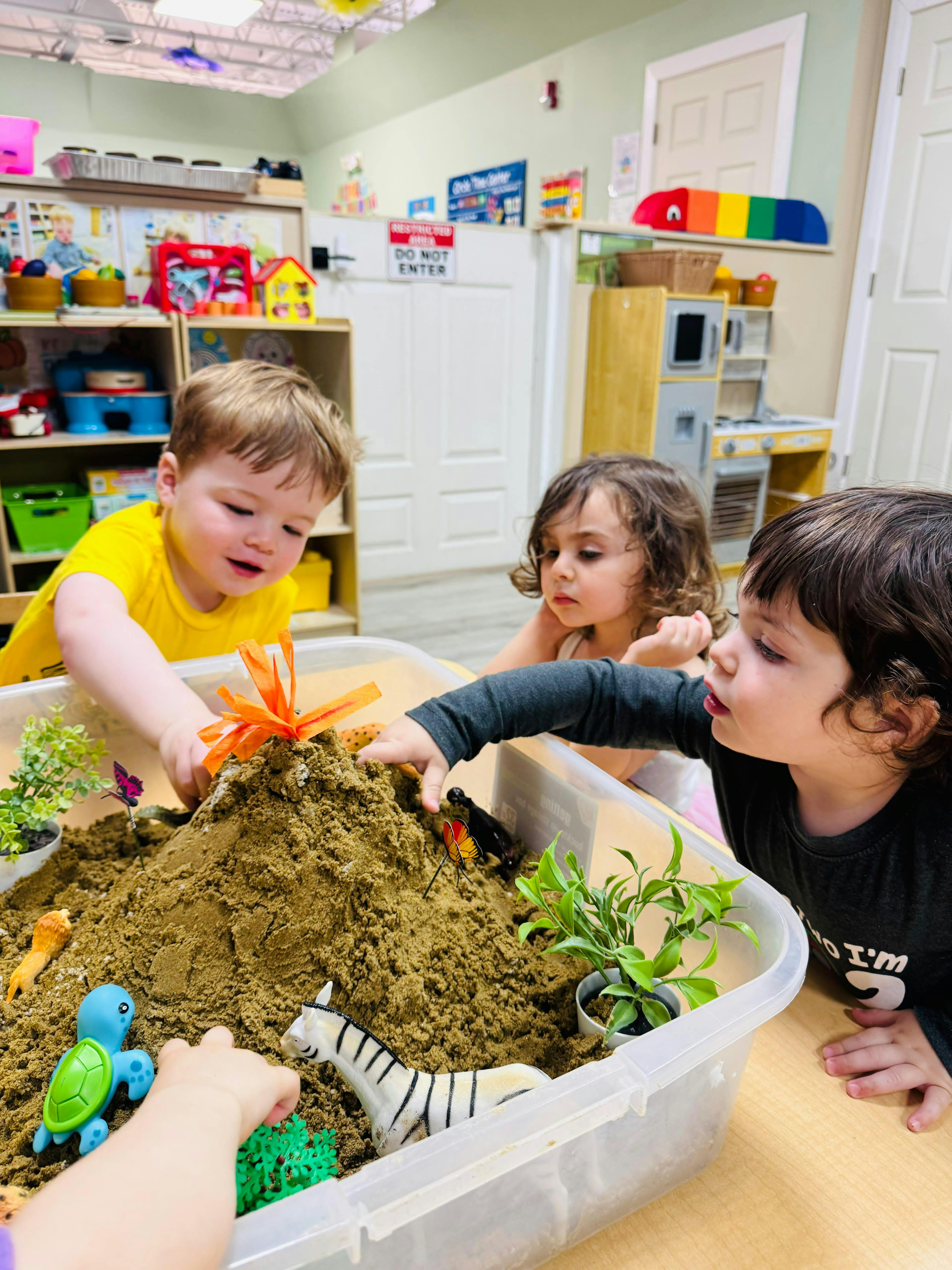 Children playing with a sand volcano sensory bin in a classroom