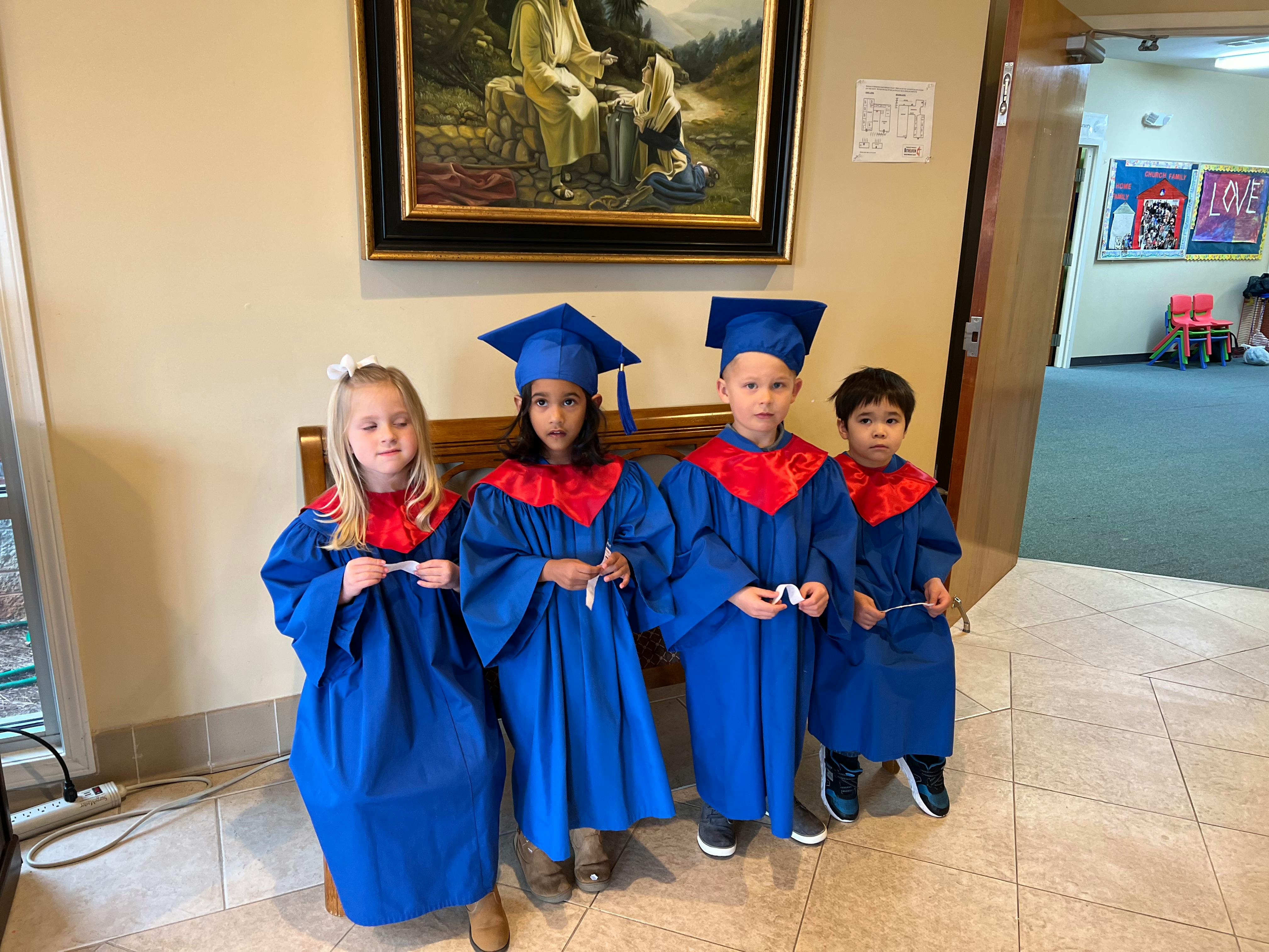 Four children in blue graduation gowns and caps