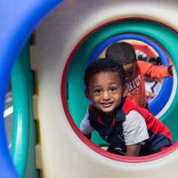 Child looking out from inside a playground tunnel