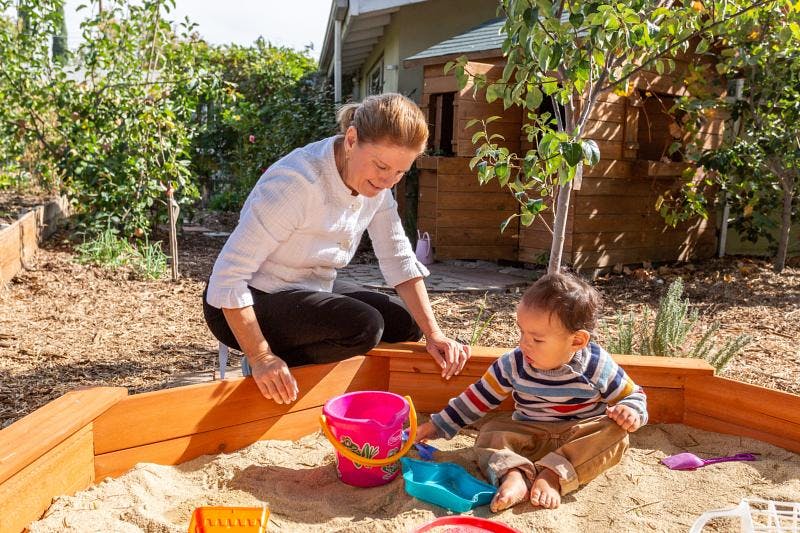 Person and child playing in a sandbox