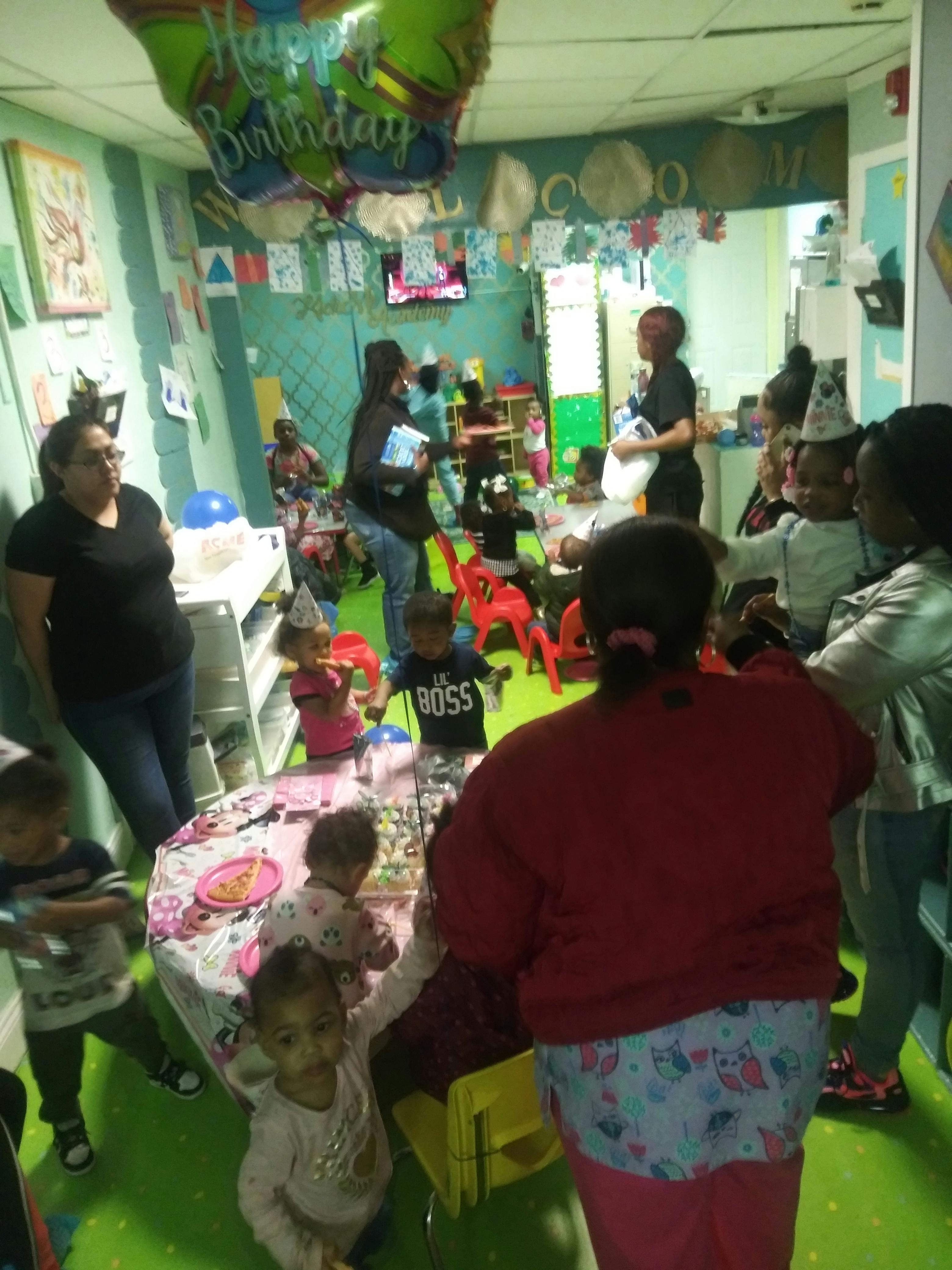 People and children gathered in a room with a Happy Birthday balloon
